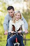 Young attractive couple rides a bicycle in the park