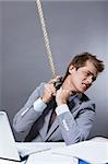 A young businessman tightens the noose on his neck