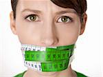 Portrait of a young  woman with a green measuring tape covering the mouth