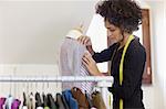 Young hispanic female dressmaker adjusting clothes on tailoring mannequin. Horizontal shape, waist up, copy space