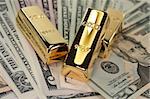 three large gold bars on many dollar bills