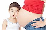 Surprised boy listening pregnant mother's belly over white background