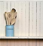 Kitchen cooking utensils; wooden spatulas etc in jar on shelf in front of rustic wall; wall allows good copy-space