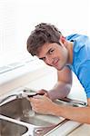 Confident man repairing his sink in the kitchen at home
