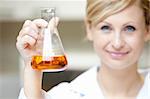 Close-up of a female scientist holding an erlenmeyer and smiling at the camera in her lab