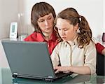 Mother and teenager girl with laptop computer together at home