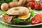 Rye bagel with salad, fried egg and bacon