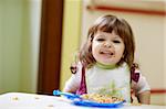 caucasian female preschooler eating pasta and smiling at camera. Horizontal shape, waist up, front view