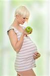 Young pregnant woman with green apple