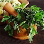 Fresh herbs (parsley, rosemary and thyme) in wooden mortar with pestle (Selective Focus, Focus on the front of the herbs)