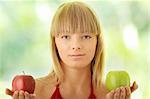 Young blond woman with red and green apples on her hand - making decision concept