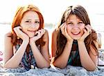 Two beautiful girls lie on the beach.