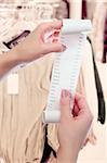 woman at shop or dry-cleaning office holds in her hands roll of paper with printed receipt