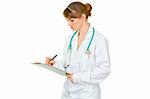 Concentrated medical female doctor making notes in document isolated on white