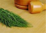 Fresh dill with wooden mortar and pestle on wooden board (Selective Focus)