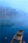 Landscape of foggy river with a wooden boat as foreground in Fenghuang county, Hunan province, China