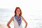 Beautiful red-haired girl at sunrise on the beach.