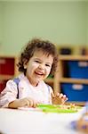 hispanic female preschooler eating pasta and smiling at camera. Vertical shape, waist up, copy space