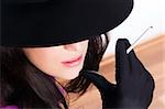 Portrait of a beautiful brunette  young woman with black hat, gloves and cigar
