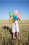 Girl with balloons at wheat field