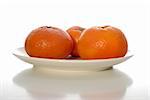 Side view of three fresh juicy tangerines on a white plate on white background.