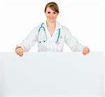 Smiling medical doctor woman holding blank billboard  isolated on white