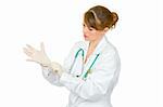 Concentrated female doctor wearing latex medical gloves on her hand  isolated on white