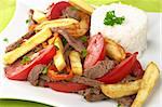 Peruvian dish called Lomo Saltado made of tomato, beef meat and onions mixed with French fries and served with rice (Selective Focus, Focus on the front)