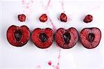image of fresh cherries cut in halves with seeds  and cherry juice on white