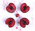 image of fresh cherries cut in halves with seed  and cherry juice on white