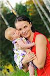 Happy mother with his daughter resting in the grass on a meadow