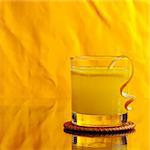 Fresh orange juice in glass with orange peel on orange background (Selective Focus)