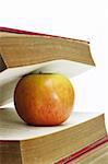 Close up of apple and old books on white background