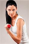 sporty woman is exercising with red barbell on grey background and looking at camera