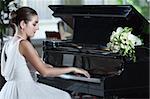 Young beautiful bride playing the grand piano