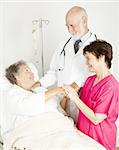 Attentive doctor and nurse caring for an elderly hospital patient.