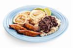 Delicious Cuban dinner with roast pork, black beans and rice, and fried plantains.  Isolated on white background
