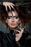 High fashion model in black dress, with long nails, creative hairstyling and makeup