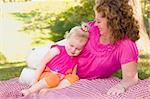 Loving Moment with Attractive Mother and Adorable Daughter on Picnic Blanket in the Park.