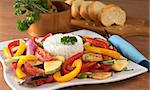 Ratatouille of zucchini, eggplant, tomato, bell pepper and onion with cooked rice and mortar with herbs and baguette in the back (Selective Focus, Focus on the front of the rice and the vegetable around)