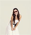 Beautiful young woman with a white dress and sunglasses showing her tongue out