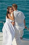 Newly married couple embracing while stood on the bow of a boat