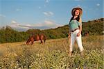 girl cowboy standing in a field with a horse nature and scope