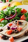 grilled swordfish with mixed salad on white towel in front of blue background