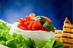 stuffed buffalo mozzarella with tomatoes and basil on lettuce over blue background