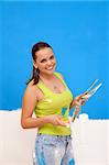 Attractive repair woman with a color guide and a paint roller in her hands