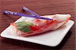 Asian spring roll in rice paper on a white plate.