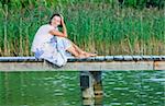 Young Woman sitting on a pier and looking at the water.