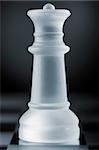 glass chess queen is standing on board in dark