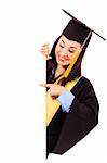 Stock image of happy female graduate pointing towards copy space on blank board